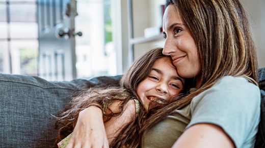 Mother and daughter hugging on couch
