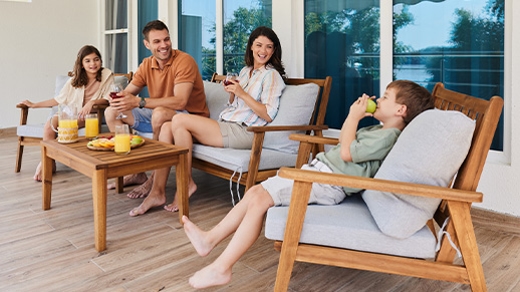 Dad, mom, son, and daughter relaxing in chairs on porch during summer