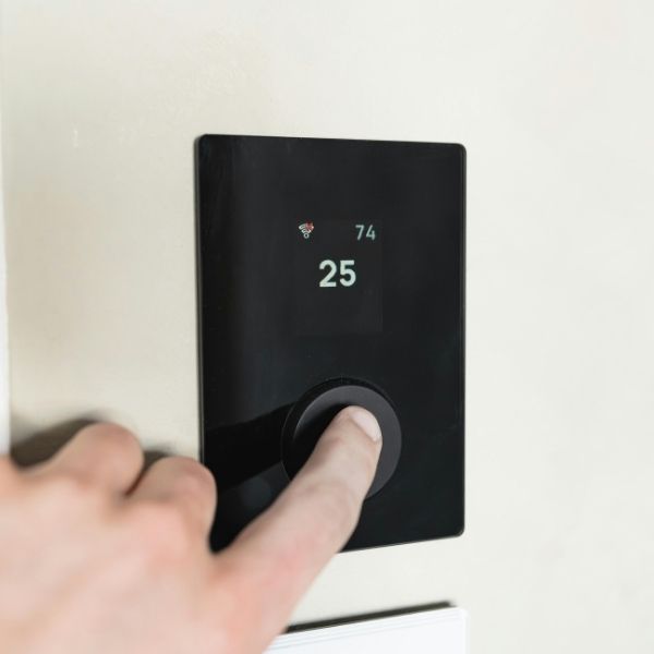 person pressing button on the thermostat