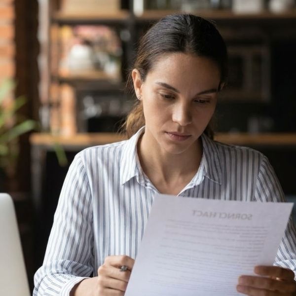 A professional woman at a desk carefully reviews a service agreement document.